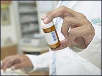 Pharmacist holds a prescription drug bottle.