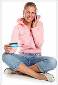 A girl holds a credit card and a cell phone.