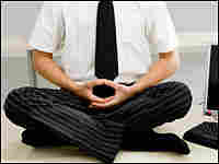 A man meditates on his desk.