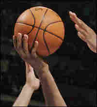 Hands of players grasping for basketball.