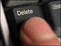 Finger pressing Delete key on computer keyboard.
